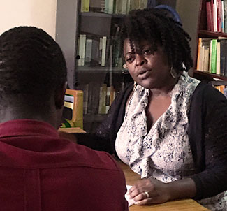 Dr. Gigi Bastien speaks with a study participant who is seated across from her at a table