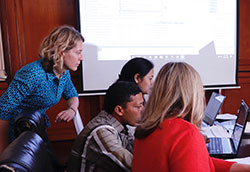 Dr. Virginia LeBaron collaborates with a team of researchers around a table of computers in Nepal.