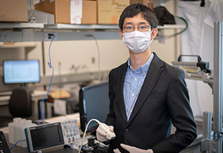 Dr. Haichong Zhang works with computer equipment in a lab wearing a mask.