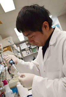 Japanese scientist Dr. Shogo Takahashi wearing white lab coat works in NIH lab with samples