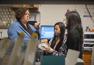 Dr. Marcy Balunas trains two female researchers in a lab