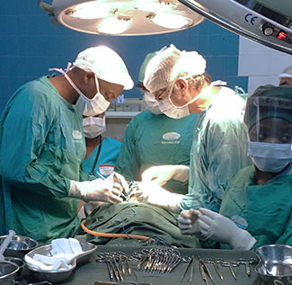 Dr. Matchecane Cossa performs surgery on a patient in an operating theater with 4 other medical workers.