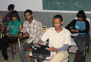 Five students seated in a classroom, all using tablet computers