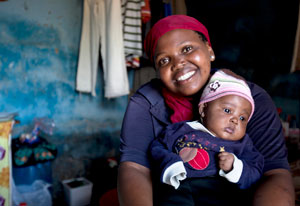 Young woman smiling at camera holds young baby