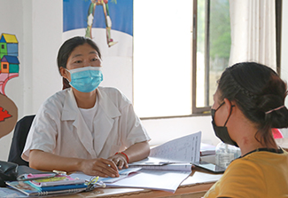 In the photo, a masked patient speaks with her doctor at a hospital in the Lao PDR. 
