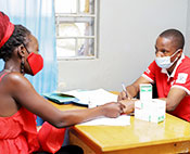 The photo shows a nurse interacting with a young woman at a family planning clinic within a government health care center in Uganda.