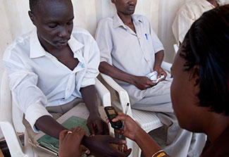 A researcher off camera collects vital signs from a seated research subject