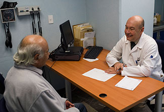 Researcher taking notes sits across from patient at desk