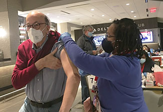 Fogarty Director Dr. Roger Glass receives a covid vaccine from a healthcare worker at a vaccine clinic.