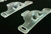 Two AdaptAir devices on black background, triangular clear plastic, nose shaped with slots for straps on both ends and top