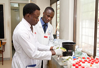 Two researchers in lab coats work in a lab preparing materials