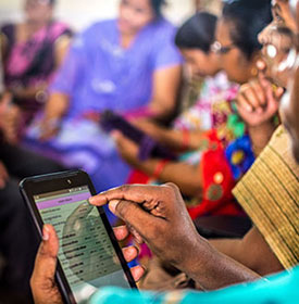 Woman uses smartphone, large group of women in the background also using smartphones