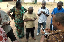 Man leads a discussion holding a handheld device, while a group of 6 additional people follow along on their own devices