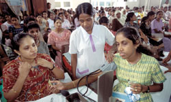 Photo: A Sri Lankan woman has her blood pressure checked by a health education nurse in a crowded clinic