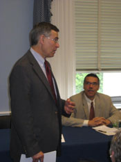 PHOTO: Rep Rush Hold stands and speaks, with Dr. Michael Johnson seated in the background