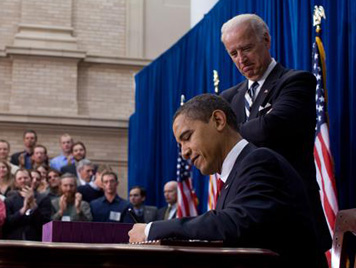 President Obama signing the Act while Vice President Joe Biden looks on.