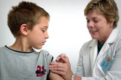 Photo: Woman nurse administers shot in upper arm of boy with sleeve rolled up