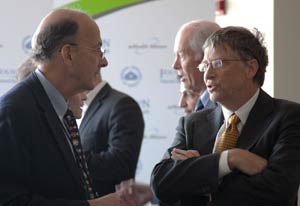 Dr Roger I Glass speaks with Bill Gates, crowded exhibit hall in background