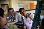 Male and female medical students look at x-ray film, held at an angle by another person who is mostly off camera